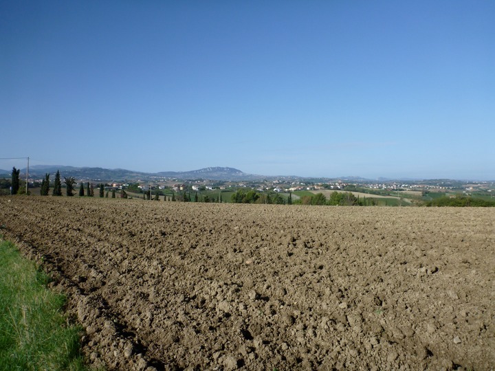 San marino in the distance past plowed-under field